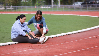 Two slim and plus size woman with sport jacket together stretch warm-up exercise on an outdoor running track, wellness and healthy lifestyle