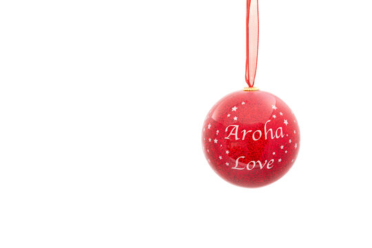 A beautiful shiny red Christmas bauble seen against a plain white background. The words Aroha and Love are written as a sentiment on the front face of the decoration.