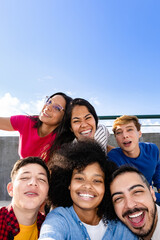 Happy multiracial friends taking selfie in city park with sky on background. Diverse young people hang out together. Vacation holidays and lifestyle concept