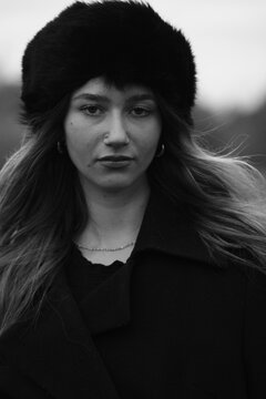 Woman fashion portrait in a black winter fur hat. Vind in hair	