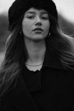 Woman fashion portrait in a black winter fur hat. Vind in hair	