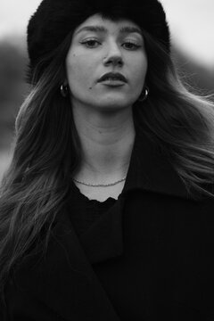 Woman fashion portrait in a black winter fur hat. Vind in hair	