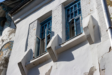 Weathered facade of an abandoned early 20th-century Art Nouveau estate with peeling blue window frames against white walls