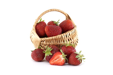 Fresh strawberries spilling from wicker basket on white background