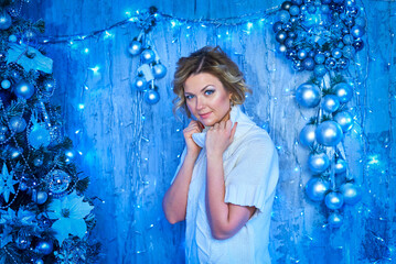 A woman in a white sweater stands in front of a Christmas tree on New Year's Eve.