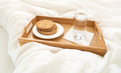 Tray with water and crackers breakfast on a bed