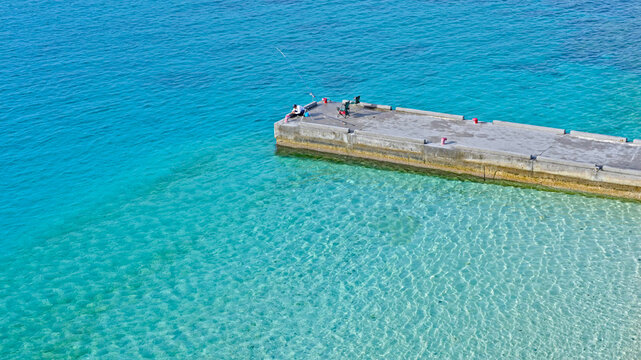 Aerial view of a pier on a beach with crystal clear water