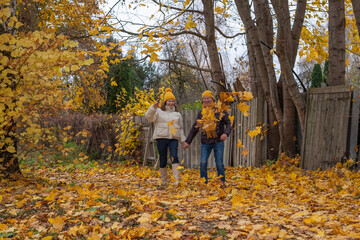 Midlife couple enjoying autumn day, playfully tossing yellow leaves in the air, surrounded by vibrant fall foliage and a serene backyard atmosphere with copy space