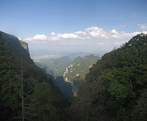 Tianmen Mountain valley view with distant Zhangjiajie city on sunny day