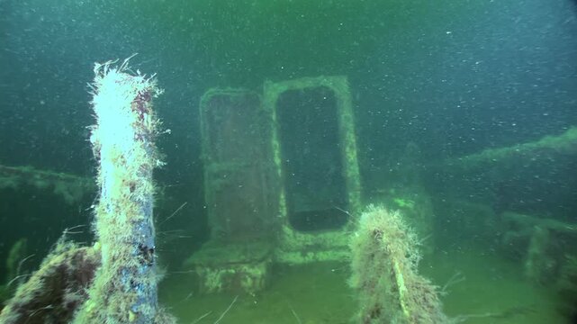 Sunken structure lies still in the dark depths of the White Sea. Algae and marine life cover the decaying ruins, creating an eerie, underwater graveyard.