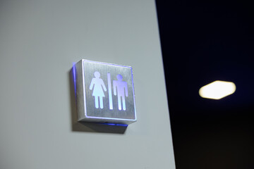 Modern restroom signage in an industrial setting with unique lighting features