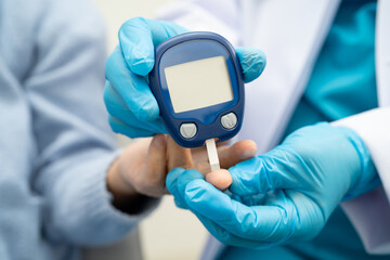 Asian doctor using digital glucose meter for check sample blood sugar level to treatment diabetes.
