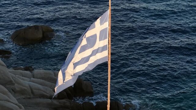 National Flag of Greece Waving on Pole at Coats Above Sea, Drone Aerial View