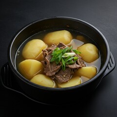 A bowl of gamja guk 메추리알 조림 (potato soup) with beef and green onions, served in a black pot against a black background. captures the hearty potatoes and clear broth, with warm lighting
