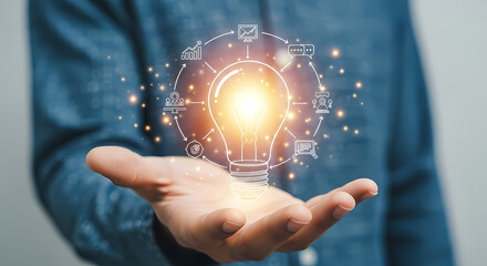 A person's hand holds a glowing lightbulb with digital icons, representing innovation, ideas, and technological advancements in a modern context.