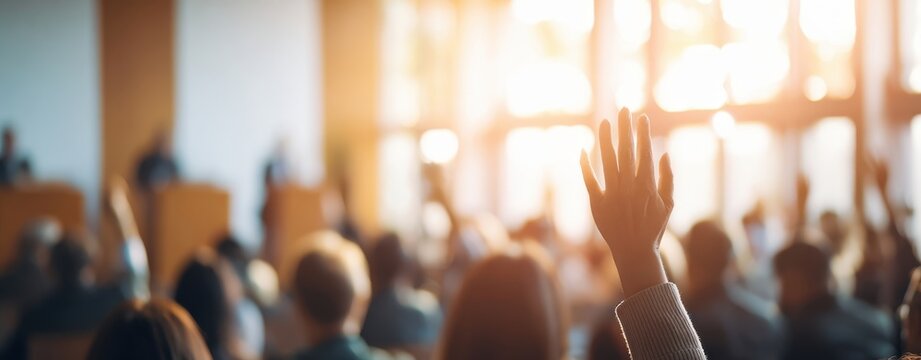The Raised Hand of an Audience Member in a Sunlit Conference Hall During Questions