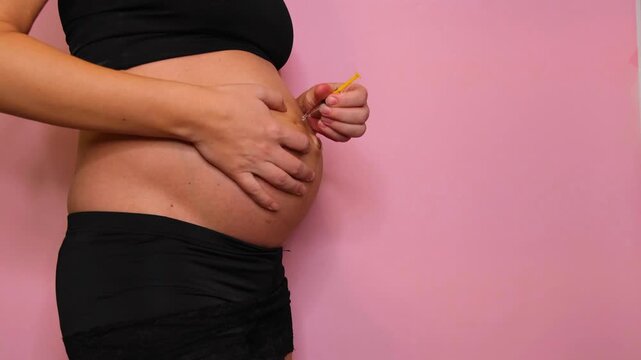 Pregnant woman giving herself a medical injection in the belly for health or fertility treatment. Self administered medicine concept.
