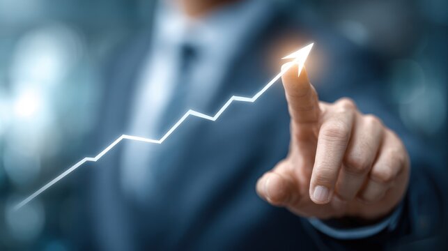 Businessman touches glowing upward trending line graph with finger.