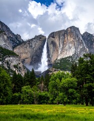A dramatic waterfall cascades from a rocky cliff with lush greenery in front