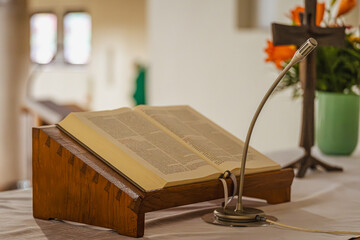 Hier treffen zwei Welten aufeinander: Das schwere, alte Buch, das die Stille vergangener Weisheit atmet, liegt bereit auf dem Pult. Es ist die unvergängliche Essenz der geschriebenen Wahrheit.