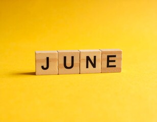 Wooden letter blocks spelling "JUNE" on a bright yellow background