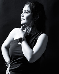 High-contrast monochrome portrait of an elegant woman in a one-shoulder dress and wrist accessories, looking upward with a confident expression. Ideal for editorial, fashion, and empowerment themes.
