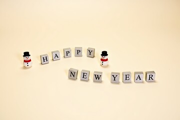 Charming snowman figurines and blocks spell happy new year on a soft background
