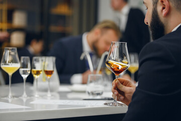 Sommelier looking at color of drink during alcohol beverages training. Training of restaurant staff, studying alcohol list.