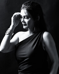 Black and white portrait of an elegant woman in a one-shoulder black dress with soft side lighting. Perfect for fine-art, fashion, and editorial photography representing confidence and beauty.