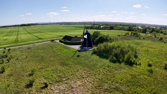 Aerial drone footage of Ega Mill in Denmark surrounded by open farmland and green fields under a bright summer sky, showcasing rural countryside scenery