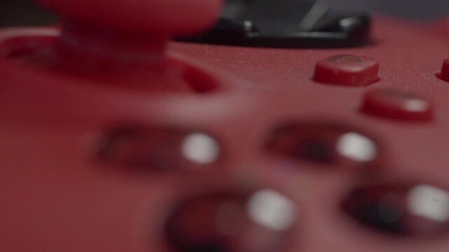 Slow Macro and closeup on red game console controller with joystick and slowly sliding over shiny buttons