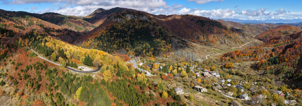 Autumn aerial panorama of Dardh&euml; in Albania showing vibrant forests, winding mountain roads and the village nestled in a colourful alpine valley.