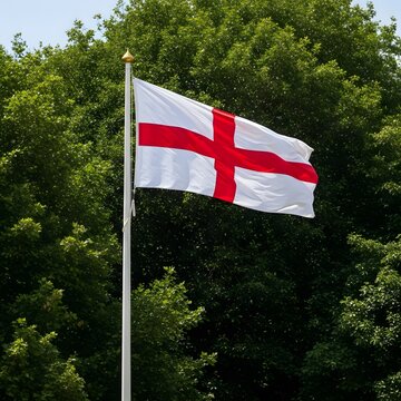 England&rsquo;s Saint George cross flag waving in sunlight, surrounded by bright green foliage and blue summer skies