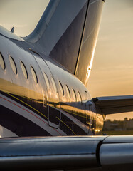 Close-up view of the tail and wing of a private jet during the golden hour.