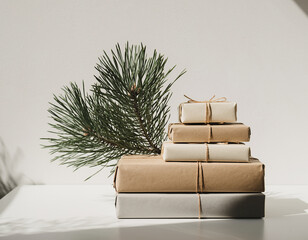 A stack of minimalist wrapped gifts with a pine branch on a white background.