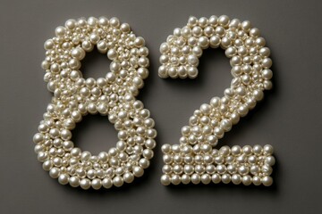 Elegant Display of Number 82 Formed by White Pearls on Gray Surface