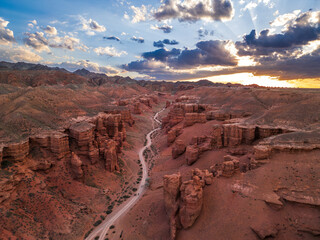 Aerial sunset view of Charyn Canyon with dramatic red cliffs, winding valley and glowing sky....