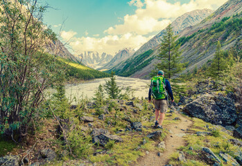 A hiker walking through a scenic mountain landscape. Backpacking is a way to immerse yourself in nature, exploring remote areas and enjoying breathtaking scenery.