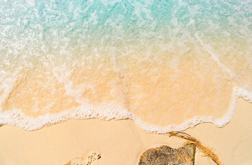 The image shows a close-up of sea foam rolling onto a sandy beach. The clear dividing line between the foam and the dry sand creates a minimalist and abstract visual effect.