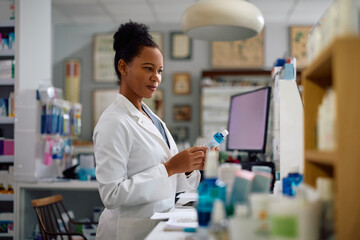 Smiling black female pharmacist working in drugstore.