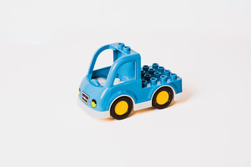 A vibrant blue toy truck sits on a bright white surface. The truck features yellow wheels and a blocky design, inviting creative playtime for children.