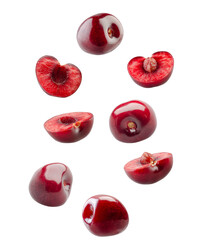 collection of whole and halved ripe dark red cherries floating and falling, showing the rich flesh and pits, isolated on a stark transparent background.