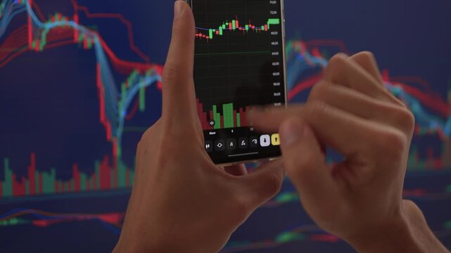 Trader observes price fluctuations closely, Hands manipulate trading charts intensely during session, Trader focuses on chart patterns and volume data to make informed choices