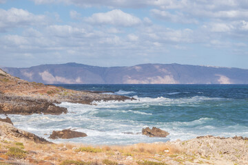Powerful surf hitting rocks emerald blue sea white foam and clear sky
