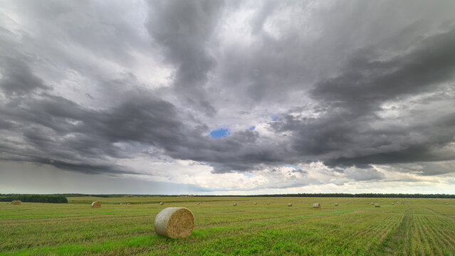 A Dramatic Sky Over Expansive Rolling Fields Filled with Hay Bales, Natures Beauty Unfolding