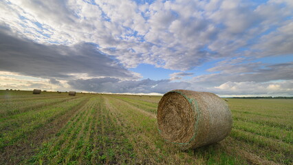 A Beautifully Captivating Rural Landscape Featuring Hay Bales Beneath A Dramatic Sky