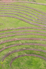 Moray, Cusco, Peru: aerial-style view of ancient Inca agricultural terraces with tourists walking on the upper level. Fine art travel photograph capturing geometry, color and history.