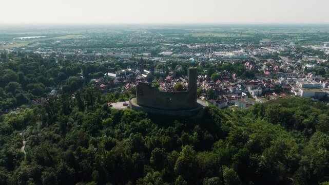 Drone panning behind Dilsberg Castle overlooking Heidelberg, Germany, with the castle in backlight and the valley filled with houses under the evening sun.