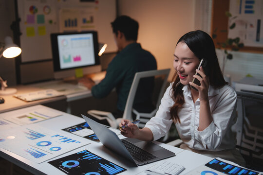 Smiling businesswoman talking on phone analyzing data in office