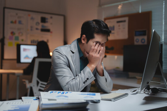 Young businessman suffering from stress working overtime in office